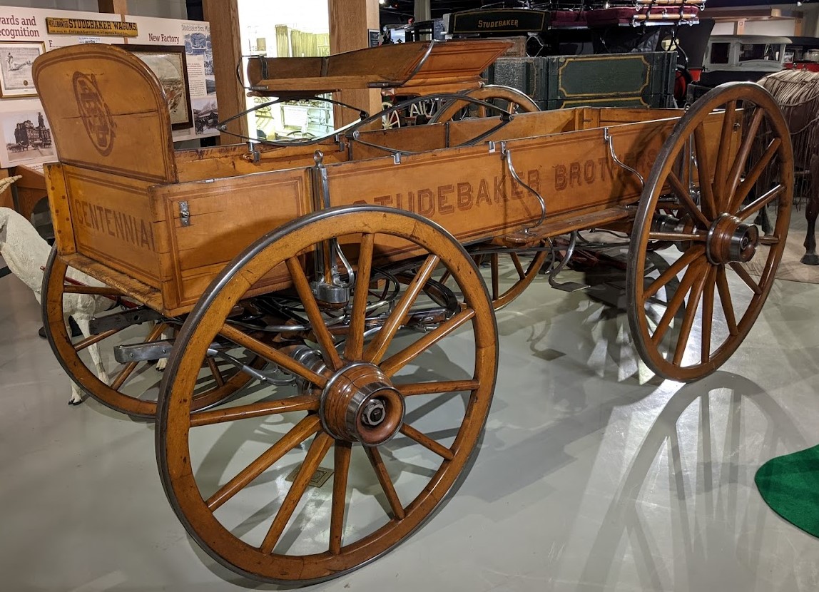The 1876 Centennial Wagon features inlaid wood in dark color to contrast with the lighter body of the wagon. There are many silver embellishments on the wagon itself.